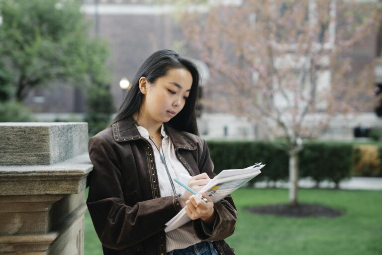 Young woman studying with papers at university campus outdoors.